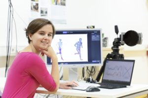 A woman with short brown hair sits in front of a computer