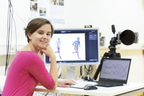 A woman with short brown hair sits in front of a computer