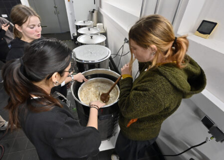 3 female Students standing around a brew kettle.