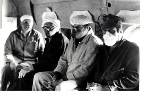 Black and white photo of people wearing protective masks.